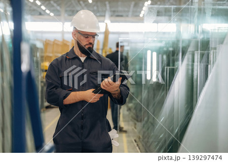 Production conception, quality control. Warehouse worker in an industrial environment of a factory or storage area Production conception, quality control. Warehouse worker in an industrial environment of a factory or storage area 139297474