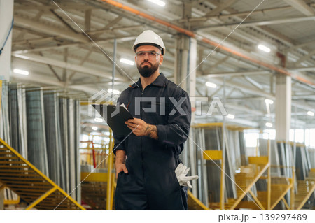 In professional protective hat. Warehouse worker in an industrial environment of a factory or storage area In professional protective hat. Warehouse worker in an industrial environment of a factory or storage area 139297489