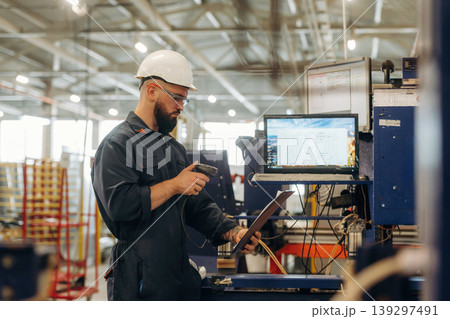 In professional protective hat. Warehouse worker in an industrial environment of a factory or storage area In professional protective hat. Warehouse worker in an industrial environment of a factory or storage area 139297491
