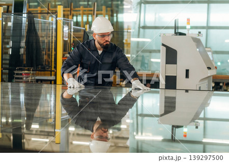 Process of preparing glass for windows. Warehouse worker in an industrial environment of a factory or storage area 139297500