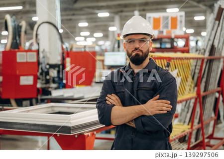 Break time, standing with arms crossed. Warehouse worker in an industrial environment of a factory or storage area 139297506