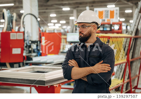 Break time, standing with arms crossed. Warehouse worker in an industrial environment of a factory or storage area Break time, standing with arms crossed. Warehouse worker in an industrial environment of a factory or storage area 139297507