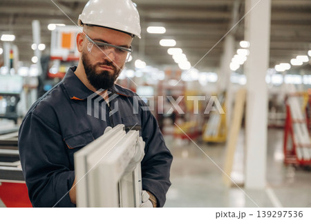 Checking quality of small window border. Warehouse worker in an industrial environment of a factory or storage area Checking quality of small window border. Warehouse worker in an industrial environment of a factory or storage area 139297536