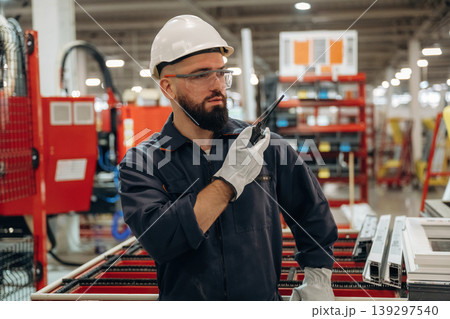 Talking by walkie talkie. Warehouse worker in an industrial environment of a factory or storage area Talking by walkie talkie. Warehouse worker in an industrial environment of a factory or storage area 139297540