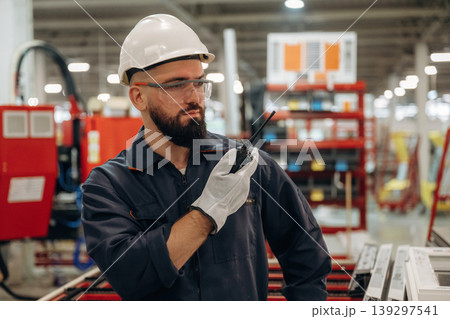 Talking by walkie talkie. Warehouse worker in an industrial environment of a factory or storage area Talking by walkie talkie. Warehouse worker in an industrial environment of a factory or storage area 139297541