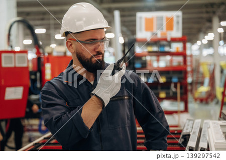 Receiving orders by walkie talkie. Warehouse worker in an industrial environment of a factory or storage area 139297542