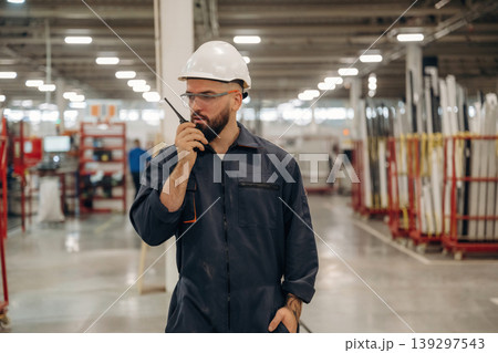 Receiving orders by walkie talkie. Warehouse worker in an industrial environment of a factory or storage area 139297543