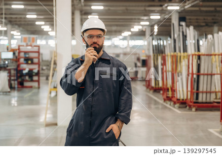 Receiving orders by walkie talkie. Warehouse worker in an industrial environment of a factory or storage area Receiving orders by walkie talkie. Warehouse worker in an industrial environment of a factory or storage area 139297545