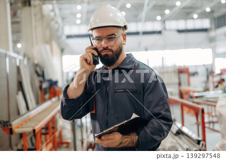Conversation by walkie talkie. Warehouse worker in an industrial environment of a factory or storage area Conversation by walkie talkie. Warehouse worker in an industrial environment of a factory or storage area 139297548