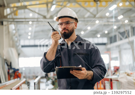Radio talking, using walkie talkie. Warehouse worker in an industrial environment of a factory or storage area Radio talking, using walkie talkie. Warehouse worker in an industrial environment of a factory or storage area 139297552
