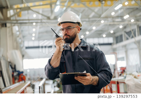 Radio talking, using walkie talkie. Warehouse worker in an industrial environment of a factory or storage area Radio talking, using walkie talkie. Warehouse worker in an industrial environment of a factory or storage area 139297553