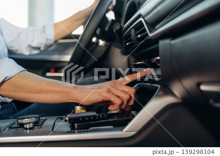 Using the control panel. Detailed close up view of woman that is driving the new car 139298104