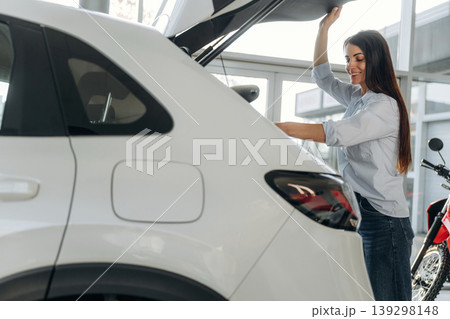 View from the side. Side view of woman that is after shopping, putting bags into the trunk of a car View from the side. Side view of woman that is after shopping, putting bags into the trunk of a car 139298148