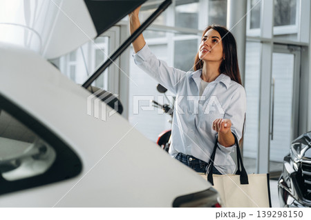 Side view of woman that is after shopping, putting bags into the trunk of a car 139298150