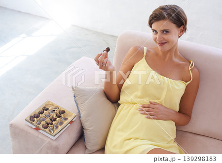 Portrait, pregnant woman and eating chocolate in home, alone and happiness for delicious pregnancy craving. Good mood, comfort food and candy dessert for maternity, snack and sweet tooth satisfaction Portrait, pregnant woman and eating chocolate in home, alone and happiness for delicious pregnancy craving. Good mood, comfort food and candy dessert for maternity, snack and sweet tooth satisfaction 139298183