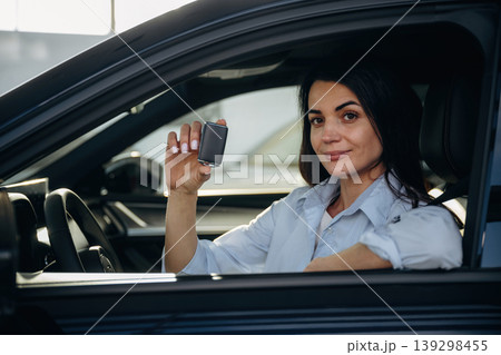 Showing the keys that are in hand. Woman is sitting in the modern car, happy new owner 139298455