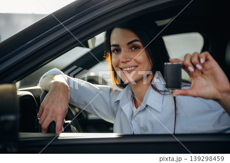 Through the window, holding keys. Woman is sitting in the modern car, happy new owner 139298459