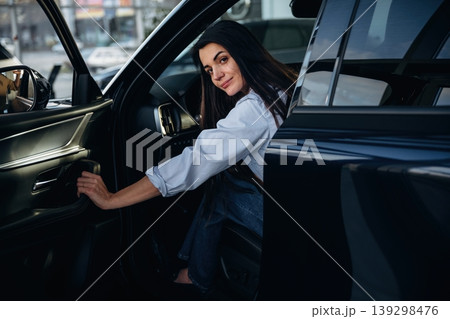 Closing the door. Woman is sitting in the modern car, happy new owner Closing the door. Woman is sitting in the modern car, happy new owner 139298476