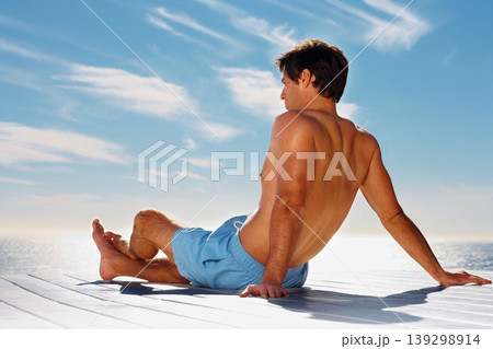 Ocean, relax and shirtless man on a deck with a view of the water in summer while on holiday or vacation. Freedom, sea or sky and the body of a young tourist tanning outdoor on a pier with space 139298914