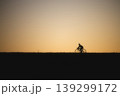 夕焼けの丘を走るサイクリストのシルエット 139299172