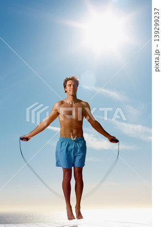 Man, shirtless or rope skipping for fitness in summer workout, muscle or happy on vacation. Model, smile or training for natural glow of sport, cardio exercise or sunshine holiday by sky background 139299237