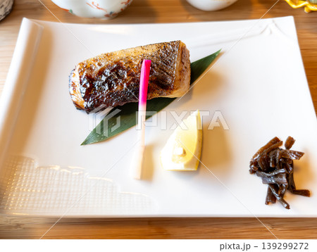 白皿に盛り付けられた鰆の西京焼きとレモンに矢生姜の和食御膳 139299272