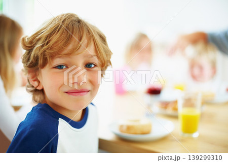 Kid, breakfast and portrait at home in the morning with food, smile and happy from eating. Family, dinner table and hungry young child with meal for health and nutrition in a house with juice 139299310