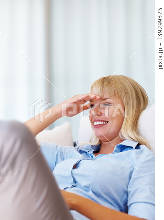 Smile, relax and young woman on a sofa with positive, good and confident attitude for peace. Happy, rest and female person from Australia laying on couch in the living room at modern apartment. 139299325
