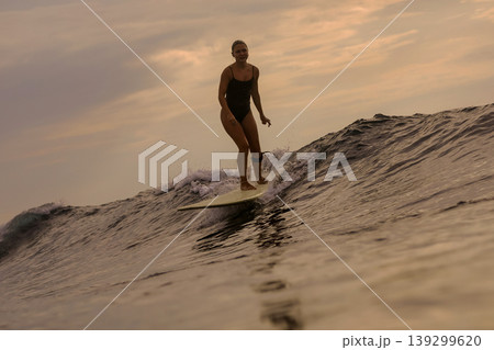 Woman Surfs Sunset, Sunset Illuminates Ocean As Woman Surfs Closer 139299620