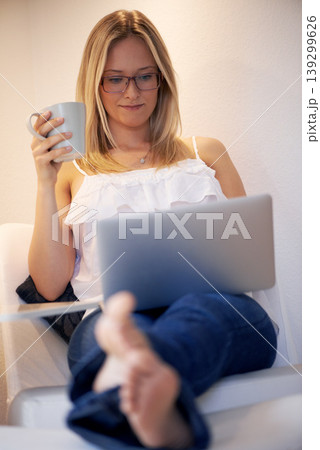 Woman, laptop and journalist with coffee in relax on chair reading, typing or writing in living room at home. Female person or freelancer smile on computer with cup of tea in remote work at house Woman, laptop and journalist with coffee in relax on chair reading, typing or writing in living room at home. Female person or freelancer smile on computer with cup of tea in remote work at house 139299626