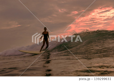 Graceful Female Surfer Enjoying Tranquil Sunset On Her Longboard Graceful Female Surfer Enjoying Tranquil Sunset On Her Longboard 139299631