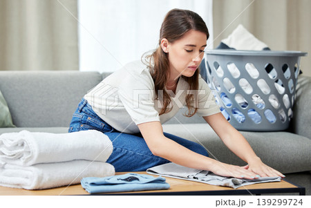 Laundry, woman and fold clothes in living room of home with housekeeping, spring cleaning and housework. Person, cleaner and packing washing on sofa in lounge with basket, serious and domestic work Laundry, woman and fold clothes in living room of home with housekeeping, spring cleaning and housework. Person, cleaner and packing washing on sofa in lounge with basket, serious and domestic work 139299724