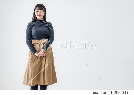 目を閉じて立つ若い女性の白背景ポートレート 139300350