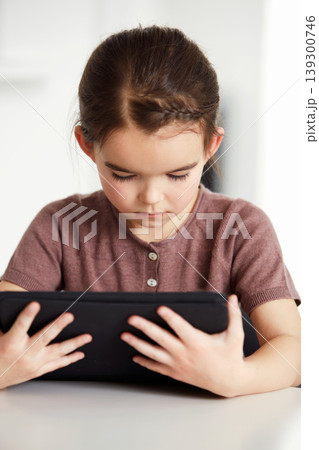Little girl, tablet and watching on table in living room for online entertainment, games or research at home. Female person, child or kid with technology for communication or networking at house 139300746