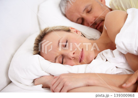 Love, tired and mature couple sleeping in bed for romantic cuddling together on weekend morning. Calm, peaceful and senior man and woman taking a nap in bedroom for bonding at modern apartment. 139300968