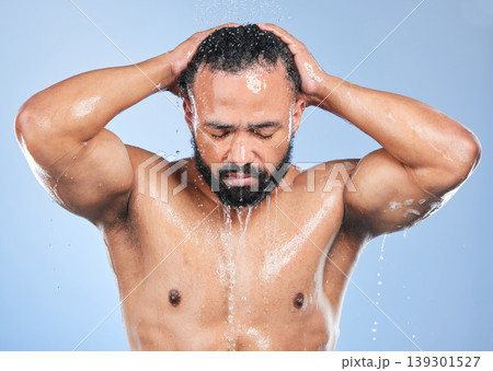 Shower, washing hair and man with water in studio for cleaning, hygiene and skincare on blue background. Dermatology, bathroom and person with drops or splash for wellness, grooming and self care 139301527