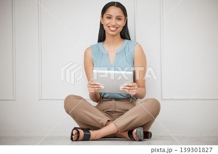 Happy business woman, tablet and sitting on floor for online communication, networking or social media at office. Portrait of female person or employee smile with technology for research at workplace Happy business woman, tablet and sitting on floor for online communication, networking or social media at office. Portrait of female person or employee smile with technology for research at workplace 139301827