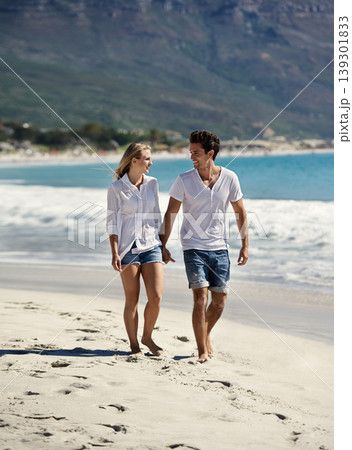 Couple, holding hands and happy on walk by ocean, vacation or freedom in summer sunshine for bonding. Man, woman and smile for talk, care or love by sea, waves or outdoor on beach holiday in Napoli 139301833