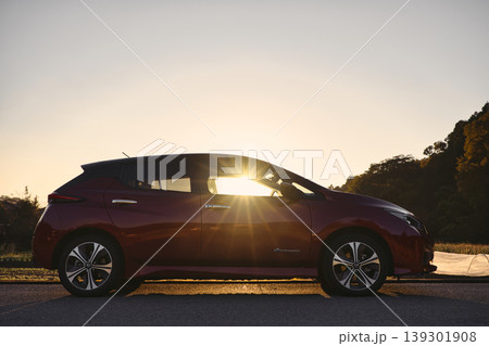 夕陽を浴びる電気自動車のシルエットと太陽の光条 夕陽を浴びる電気自動車のシルエットと太陽の光条 139301908