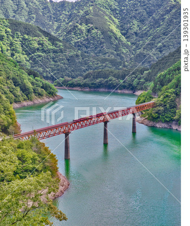 静岡の秘境 エメラルドグリーンの湖上に浮かぶ赤い鉄橋と列車 静岡の秘境 エメラルドグリーンの湖上に浮かぶ赤い鉄橋と列車 139301935