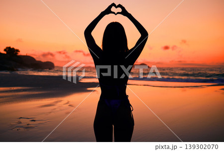 Woman, silhouette and sunset by water with heart hands for love, care and kindness with sign, summer and body. Girl, person and beach with symbol, emoji or icon on vacation, ocean or outdoor at dusk Woman, silhouette and sunset by water with heart hands for love, care and kindness with sign, summer and body. Girl, person and beach with symbol, emoji or icon on vacation, ocean or outdoor at dusk 139302070
