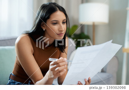 Woman, documents and reading on sofa for finance, expenses or checking bills in living room at home. Face of female person with paperwork in budget planning, investments or financial plan at house Woman, documents and reading on sofa for finance, expenses or checking bills in living room at home. Face of female person with paperwork in budget planning, investments or financial plan at house 139302098