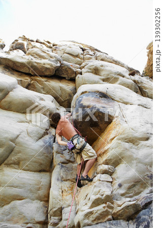 Man, mountain and rock climbing or chalk for grip as outdoor performance, adventure or gear. Male person, hanging and rope on cliff or fearless danger on boulder stone, training for exercise discover 139302256