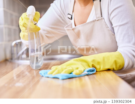 Woman, spray bottle and hands cleaning table in housekeeping, hygiene or disinfection with gloves in kitchen. Closeup of female person wiping surface, counter or furniture in bacteria or germ removal Woman, spray bottle and hands cleaning table in housekeeping, hygiene or disinfection with gloves in kitchen. Closeup of female person wiping surface, counter or furniture in bacteria or germ removal 139302304