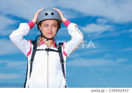Woman, skydiver and helmet in outdoors, adventure and recreation or extreme sports for fun or equipment. Female person, travel and outside or fitness, holiday and vacation or getaway by blue sky 139302437
