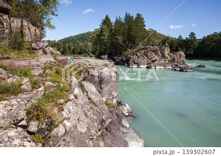 A turquoise mountain river winds around rugged rock cliffs A turquoise mountain river winds around rugged rock cliffs 139302607