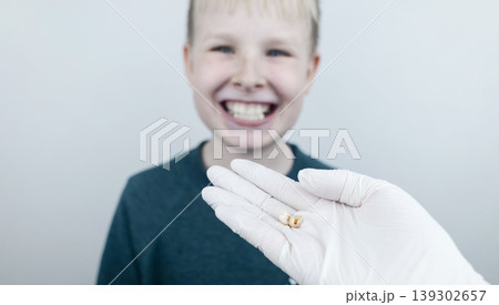 10 year old boy at pediatric dentist showing milk tooth extraction. Concept of caries treatment, physiological change of teeth and permanent teeth eruption in school age children. 10 year old boy at pediatric dentist showing milk tooth extraction. Concept of caries treatment, physiological change of teeth and permanent teeth eruption in school age children. 139302657
