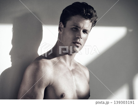 Fitness, portrait of young muscular man with confident, attractive and sexy attitude after workout. Handsome, strong and shirtless male bodybuilder with macho muscles and serious face by gray wall. Fitness, portrait of young muscular man with confident, attractive and sexy attitude after workout. Handsome, strong and shirtless male bodybuilder with macho muscles and serious face by gray wall. 139303191