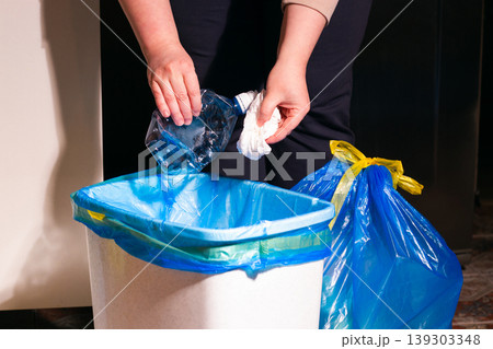 Person disposing paper and plastic together into garbage container. Illustrates the WRONG first step in waste sorting theme Person disposing paper and plastic together into garbage container. Illustrates the WRONG first step in waste sorting theme 139303348