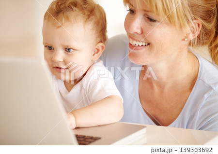 Happy, mother and baby on laptop for remote work in the living room at home for professional career. Smile, woman and little infant child while browsing online on a computer for freelance research Happy, mother and baby on laptop for remote work in the living room at home for professional career. Smile, woman and little infant child while browsing online on a computer for freelance research 139303692